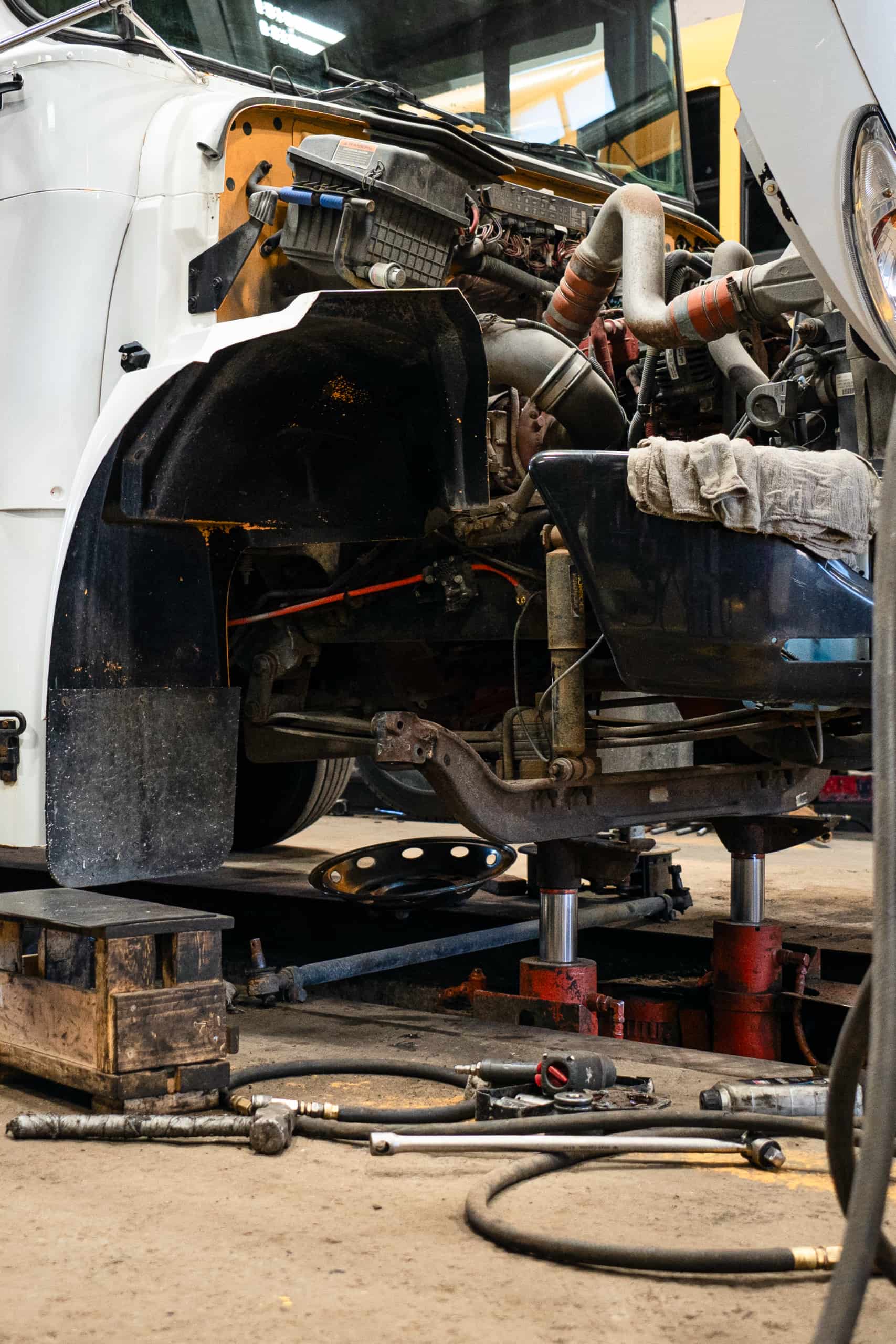 Réparation de direction de camion lourd avec cabine levée en atelier.